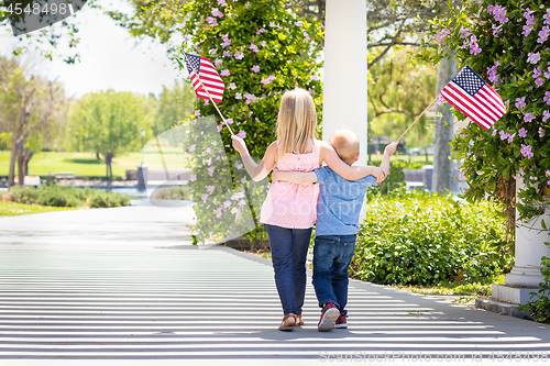 Image of Young Sister and Brother Waving American Flags At The Park