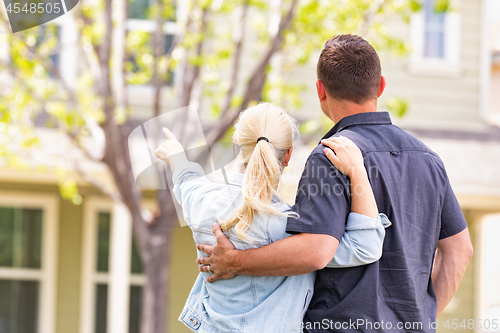 Image of Happy Caucasian Couple Facing and Pointing to Front of House