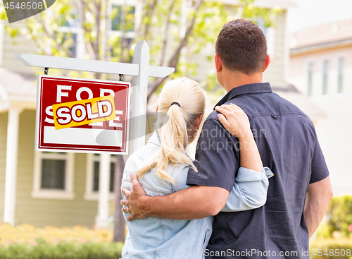 Image of Caucasian Couple Facing Front of Sold Real Estate Sign and House