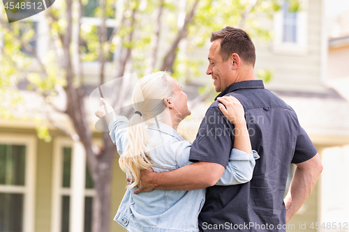 Image of Happy Caucasian Couple Facing and Pointing to Front of House