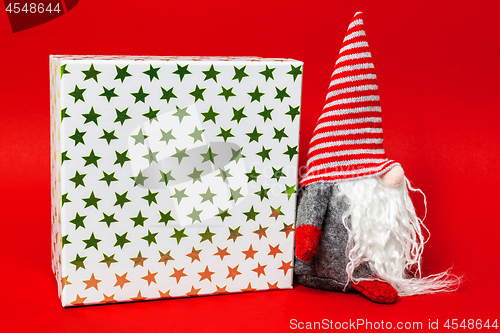 Image of Christmas decoration with a gnome and a gift box on red backgrou
