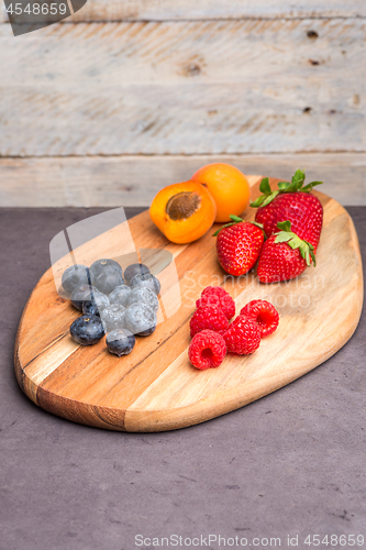 Image of Wooden board with fresh organic fruit and berries