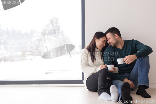 Image of multiethnic couple enjoying morning coffee by the window