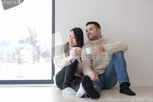 Image of multiethnic couple enjoying morning coffee by the window