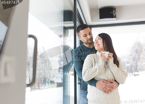 Image of multiethnic couple enjoying morning coffee by the window