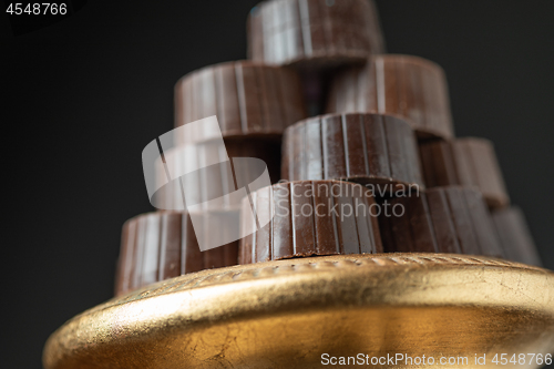 Image of Stack of Fine Chocolates On Golden Pillar Dish With Dark Backgro
