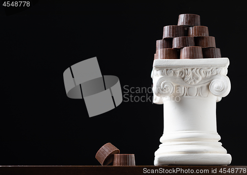Image of Stack of Fine Artisan Chocolates Stacked On White Pillar Column