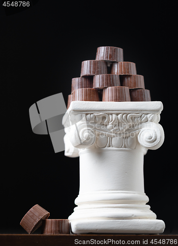 Image of Stack of Fine Artisan Chocolates Stacked On White Pillar Column