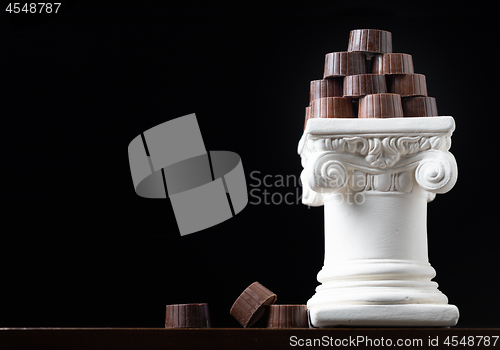 Image of Stack of Fine Artisan Chocolates Stacked On White Pillar Column