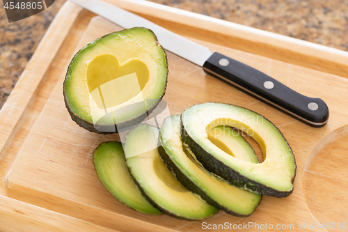 Image of Fresh Cut Avocado With Heart Shaped Pit Area On Wooden Cutting B