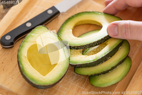 Image of Male Hand Prepares Fresh Cut Avocado With Heart Shaped Pit Area 