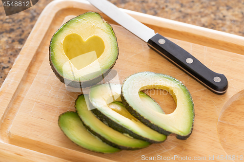 Image of Fresh Cut Avocado With Heart Shaped Pit Area On Wooden Cutting B