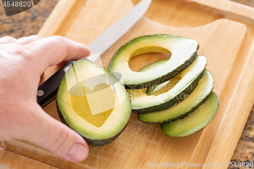 Image of Male Hand Prepares Fresh Cut Avocado With Heart Shaped Pit Area 