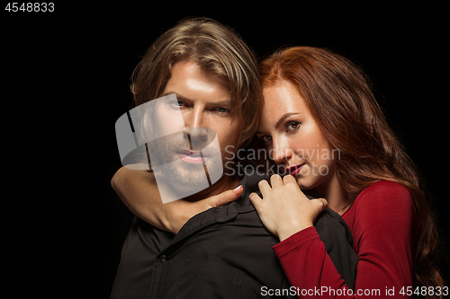 Image of Real passion. Beautiful young loving couple bonding to each other while both standing against black studio walls