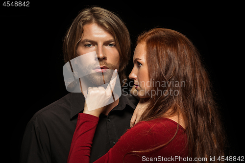 Image of Real passion. Beautiful young loving couple bonding to each other while both standing against black studio walls