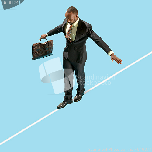 Image of Business man on tightrope concentrate to walking isolated on blue background