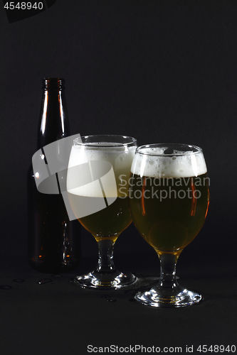 Image of Two glasses full with beer and  beer bottle.  