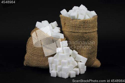 Image of Cubes Sugar in burlap bags over black. 