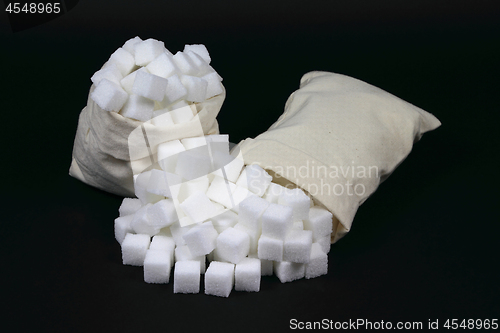 Image of Spilled Cubes Sugar from bags over black. 