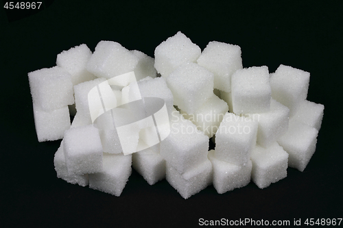Image of Spilled Cubes Sugar on pile over black. 