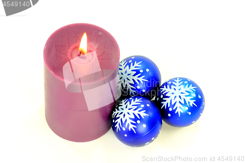 Image of Purple Burning candle and blue decoration balls. 