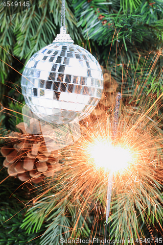 Image of Christmas tree, mirror ball and lit sparkler. 