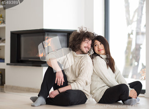 Image of happy multiethnic couple  in front of fireplace