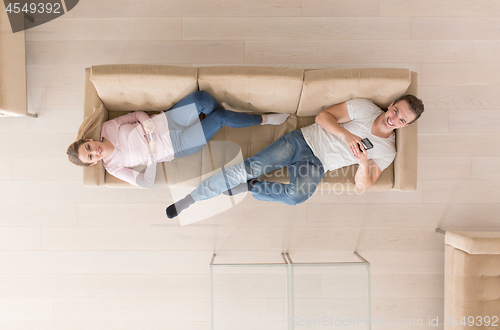 Image of Young couple on the sofa watching television top view