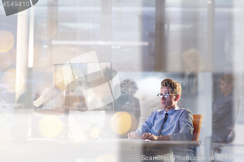 Image of man working on computer in dark office