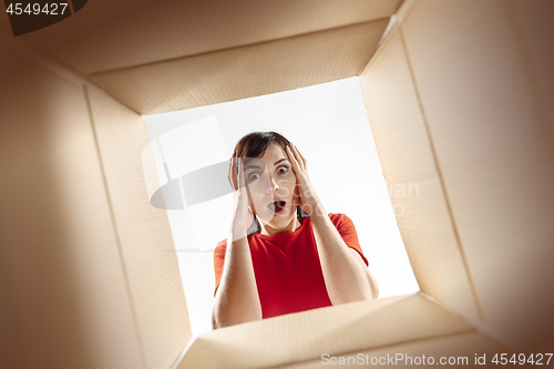 Image of Woman unpacking and opening carton box and looking inside