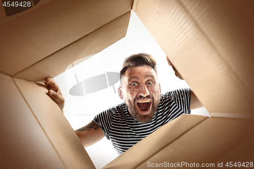 Image of Man unpacking and opening carton box and looking inside