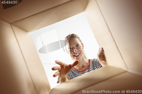 Image of Woman unpacking and opening carton box and looking inside