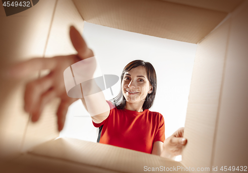 Image of Woman unpacking and opening carton box and looking inside