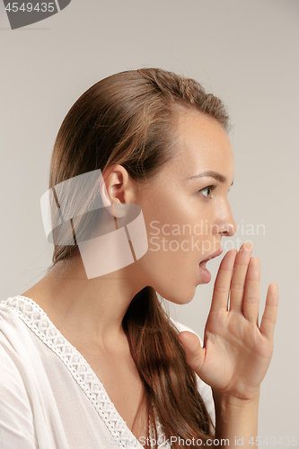 Image of The young woman whispering a secret behind her hand