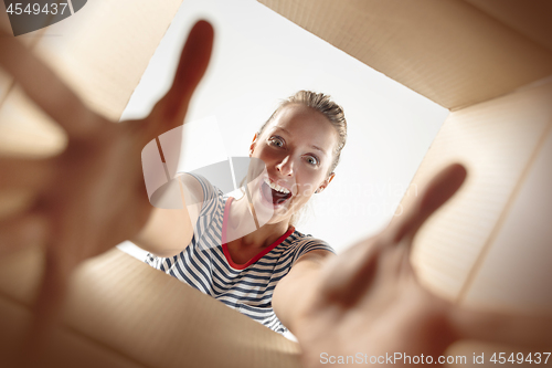 Image of Woman unpacking and opening carton box and looking inside