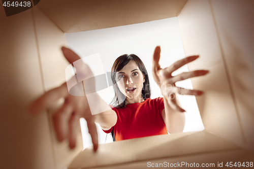 Image of Woman unpacking and opening carton box and looking inside