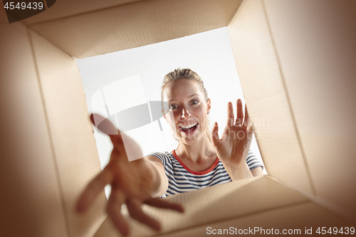 Image of Woman unpacking and opening carton box and looking inside