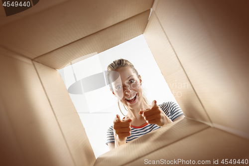 Image of Woman unpacking and opening carton box and looking inside