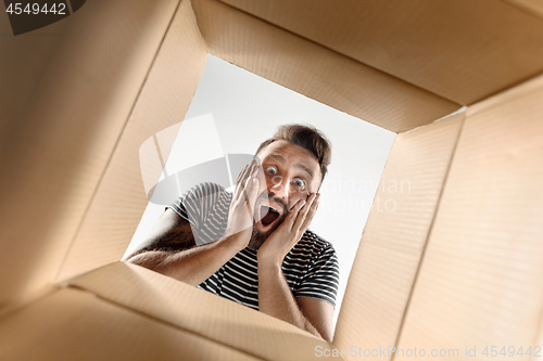 Image of Man unpacking and opening carton box and looking inside