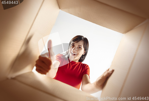 Image of Woman unpacking and opening carton box and looking inside