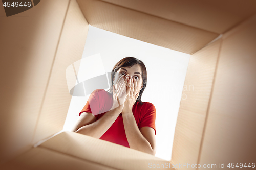 Image of Woman unpacking and opening carton box and looking inside