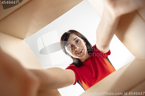 Image of Woman unpacking and opening carton box and looking inside