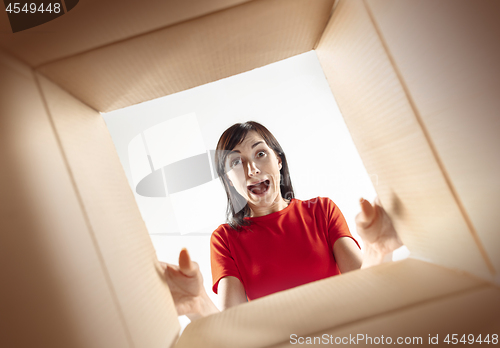 Image of Woman unpacking and opening carton box and looking inside