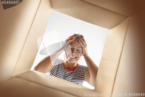 Image of Woman unpacking and opening carton box and looking inside