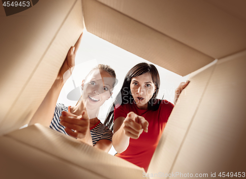 Image of Women unpacking and opening carton box and looking inside