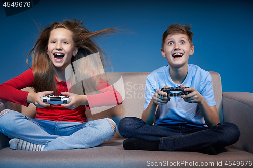 Image of Computer game competition. Gaming concept. Excited girl playing video game with joystick