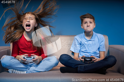 Image of Computer game competition. Gaming concept. Excited girl playing video game with joystick