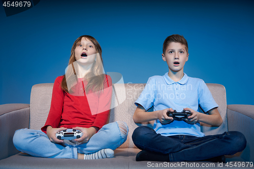 Image of Computer game competition. Gaming concept. Excited girl playing video game with joystick