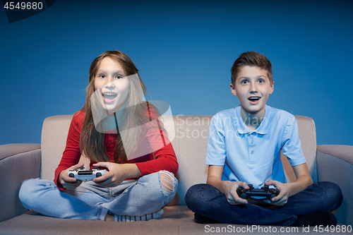 Image of Computer game competition. Gaming concept. Excited girl playing video game with joystick