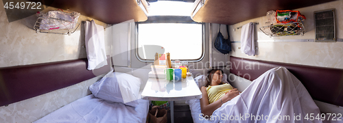 Image of Panorama of the interior of a reserved seat train car, a girl sleeping on one of the lower shelves